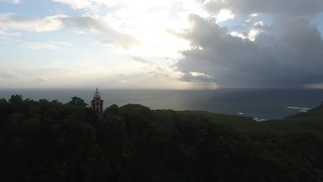 Aerial-drone-shot-Zoom-out-over-trees,-lighthouse-and-ocean-in-martinique